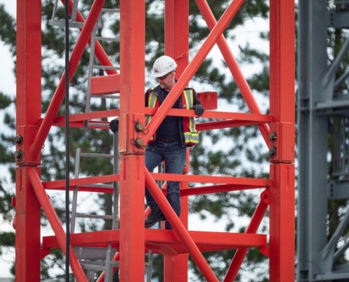 Man climbing up a red tower crane