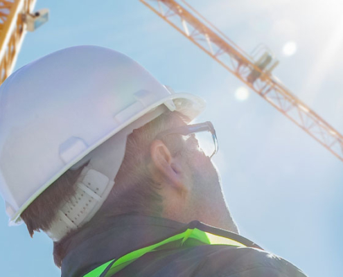 Crane operator looking up at a crane on a hot sunny day