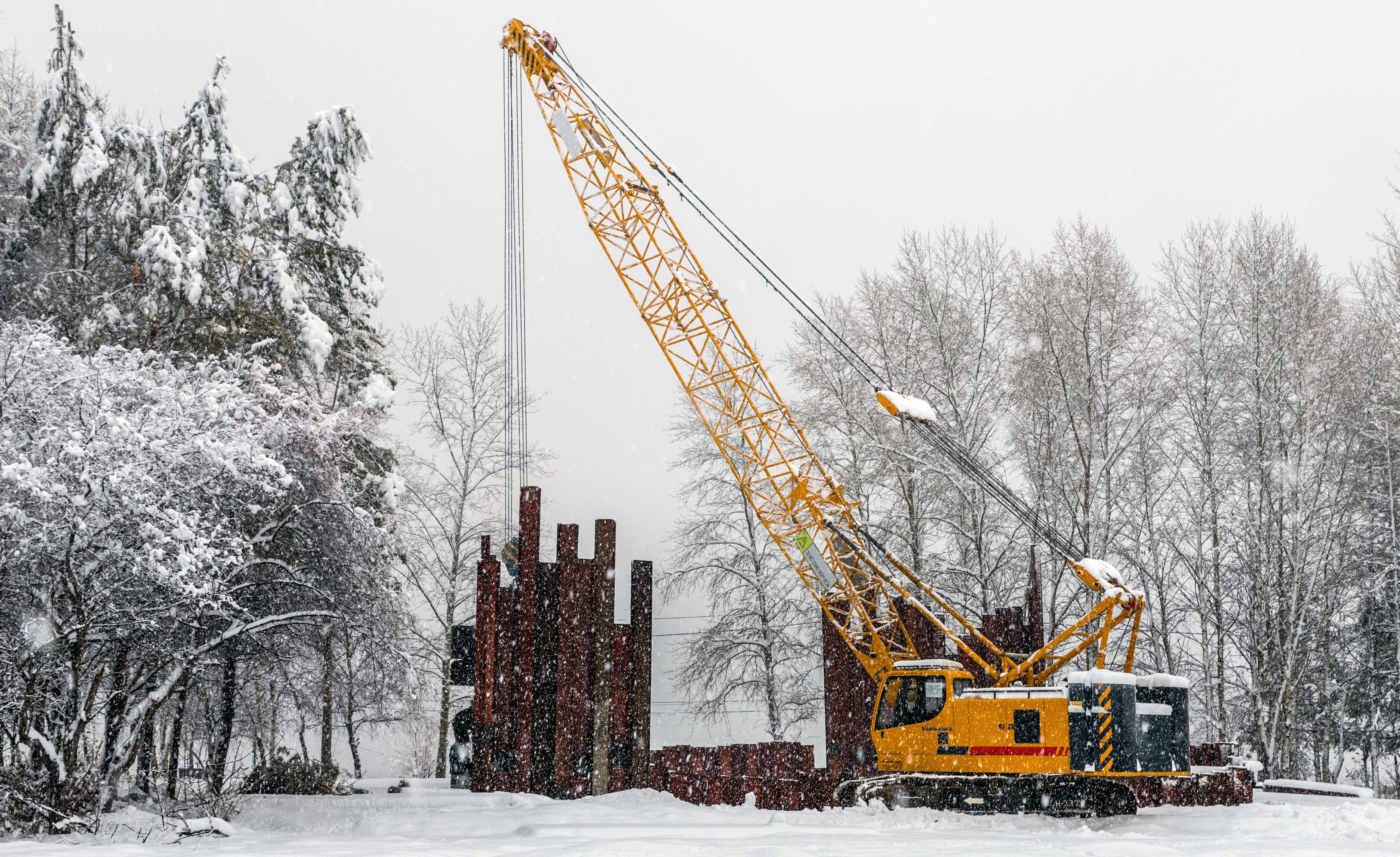Mobile crane work in a park during snowfall. Work in bad weather conditions. Mobile crane work in a park during snowfall. Work in bad weather conditions.